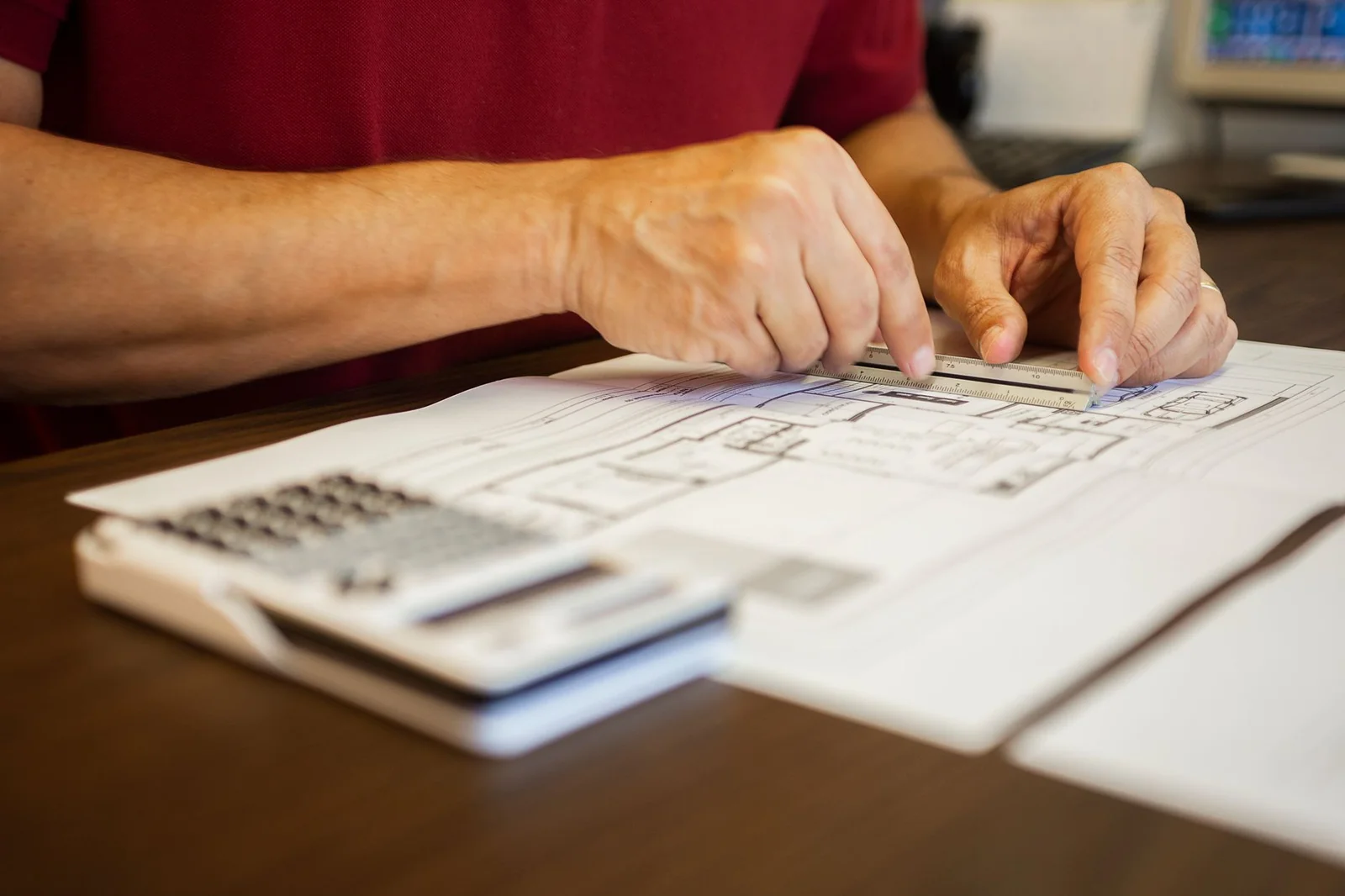 Plans d'architecte et calculatrice posés sur une table de travail